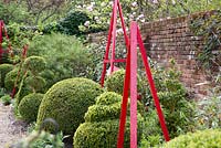Decorative obelisks and topiary shapes in The Alice Garden in spring - West Green House, Hampshire