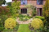 Paved courtyard with Euonymus topiary in foreground - Mount Court Farmhouse