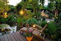Wooden deck and seating area overlooking pond at dusk