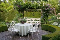 Formal seating area on paved terrace and clipped box hedges