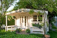 Painted summerhouse with hanging baskets 