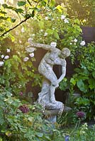 Figurative statue and climbing rose