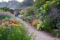 Double border with mixed July planting including Veronicastrum, Helenium, Sedum, Verbena, Stipa gigantea, Achillea Mondpagode - Parham, West Sussex