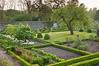 The walled garden with low, clipped hedges and planting of Malus, Brunnera, Geranium, Helleborus, Tulipa 'Purissima' and Tulipa 'White Triumphator' - Wretham Lodge, Norfolk