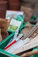 Spring time potting bench with wooden tray of gardening equipment including packets of seeds, wooden seed labels and garden twine