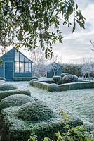 View to garden store and lean to greenhouse. Yew and box topiary and dwarf hedges on frosty morning in December - The Mill House, Little Sampford, Essex