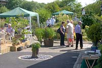 People visiting a National Garden Scheme garden in June with seating areas and gazebos