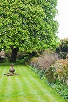 View towards magnificent horse chestnut at the end of a grassy terrace with sundial. Wayford Manor, Wayford, Crewkerne, Somerset, UK