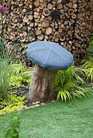 Seat in shape of mushroom made from chicken wire and tree trunk and artificial grass in modern courtyard garden 