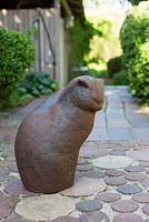 Iron cat sculpture sitting on patio of terracotta tiles and bricks - Ulla Molin 
 