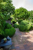 Terrace of terracotta tiles and bricks. Plants include Bamboo and Buxus and Taxus hedges and topiary - Ulla Molin 

