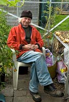 Contented gardener in his greenhouse. Yorkshireman Robert Cockroft takes a rest from work on his allotment - Warley, West Yorkshire
