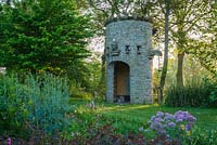 Stone dovecot that operates as a spectacular water feature as well. A simple belt and trough system scoops water up from the mill leat into a tank which, when full spouts throught the open mouth of a gargoyle back into the mill pond - Westonbury Mill
