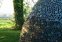 Dome structure made from thousands of bottles, with countryside beyond - Westonbury Mill