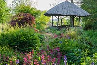African inspired thatched hut surrounded by moisture loving plants including candelabra Primulas, Aruncus, Irises, Rodgersias and Astilbes - Westonbury Mill
