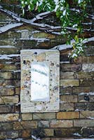 Wall plaque with mirror and sea shells reflecting snowy garden - Rhadegund House, New Square, Cambridge