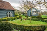 View to garden store and lean to greenhouse. Wrought iron garden table and seats. Yew and box topiary and dwarf hedges - The Mill House, Little Sampford, Essex
