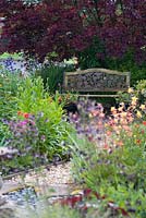 View through summer planting to ornate bench