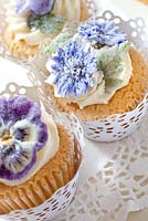 Cup cakes decorated with crystalised flowers.