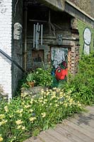 Characterful corner in brick alcove which is part of an old building with daffodils in front, Dalston Eastern Curve Garden, London Borough of Hackney, UK