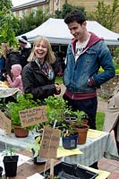 Young couple buying plants from stall at King Henry's Walk Garden, urban community allotments, London Borough of Islington, UK