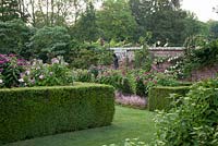 Mixed Rosa in formal walled garden with clipped Buxus hedges and Rosa 'Baronne Prevost', Rosa 'Constance Finn', Rosa 'de Rescht' and Rosa 'Souvenir du Docetur Jamain' on metal obelisk. Pashley Manor