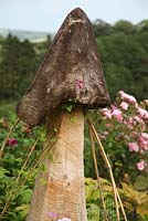 Wooden garden ornament with canes supporting a Clematis