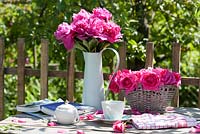 Relaxing area with table arrangements of pink flowers of peony and roses. Rosa ' Coral Dawn' and Paeonia officinalis 'Rosea Plena'