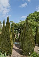 Carved limestone wellhead, Four quadrant beds are separated by tall thin yew spires in a cruciform. Wollerton Old Hall(NGS)