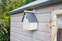 Freshly painted birdbox hanging on shed
