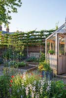 Potager in summer with greenhouse, raised beds and bench