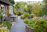 Walled courtyward garden. All planting created above ground, on top of former farmyard.  Mixed containers and beds, include Gaura lindheimeri, Anemone hupehensis, Diascia, Sedum, Clematis, mixed grasses and Betula and Rhus typhina trees - NGS garden Oxsetton