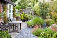 Walled courtyward garden. All planting created above ground, on top of former farmyard.  Mixed containers and beds, include Gaura lindheimeri, Anemone hupehensis, Diascia, Betula, Sedum, Clematis, mixed grasses - NGS garden Oxsetton 
