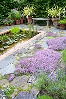 Il Vivaio, a small enclosed garden with a rectangular pond and mediterranean plants including lavenders, thymes and phormiums. Ashley Farm, Stansbatch, Herefordshire, UK