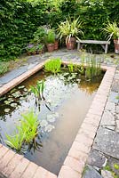 Il Vivaio, a small enclosed garden with a rectangular pond and mediterranean plants including lavenders, thymes and phormiums. Ashley Farm, Stansbatch, Herefordshire, UK