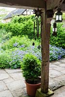 The Loggia garden is planted in shades of blue, purple and silver, with covered open barn at the end used for serving teas on open days. Ashley Farm, Stansbatch, Herefordshire, UK - view from barn 