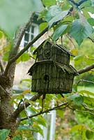 Vintage bird house hanging in tree