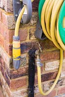 Garden hose mounted on the side of house