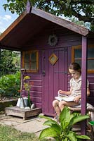 Young girl reading book beside Wendyhouse
