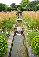 Merriments Garden with designed water feature. Border areas are a mass of golden grasses - Calamagrostis varia

