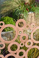 Circular designed copper fence. Anemanthele Lessoniana. The QEF Garden For Joy. 