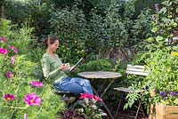 Woman reading newspaper and drinking tea in small suburban garden
