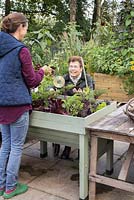 Middle aged woman assisting an elderly disabled woman with gardening