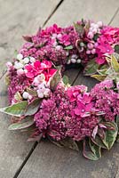 Decorative pink wreath of Snowberries, Hydrangea, Fuchsia and Sedum.