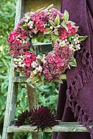 Decorative pink wreath of Snowberries, Hydrangea, Fuchsia and Sedum.