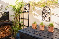 Black woodwork and cream walls make a striking combination in the back garden with constructions including a wood store with sempervivum roof and housings for compost bins
