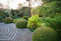 Clipped yew spheres frame the drive and the circular maze formed of stone setts laid in to the gravel