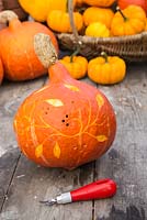 Using a lino cutter to create patterns in a pumpkin
