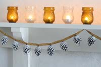 Step by step of making a Christmas garland with fir cones and ribbon - The finished garland pinned in place on a mantlepiece