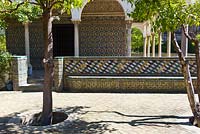 The Pavilion of Carlos V. Walls and seats decorated with Azulejos tiles in The Abode Garden with Seville Orange trees Citrus aurantium at El Real Alcázar de Sevilla Andalusia, Spain